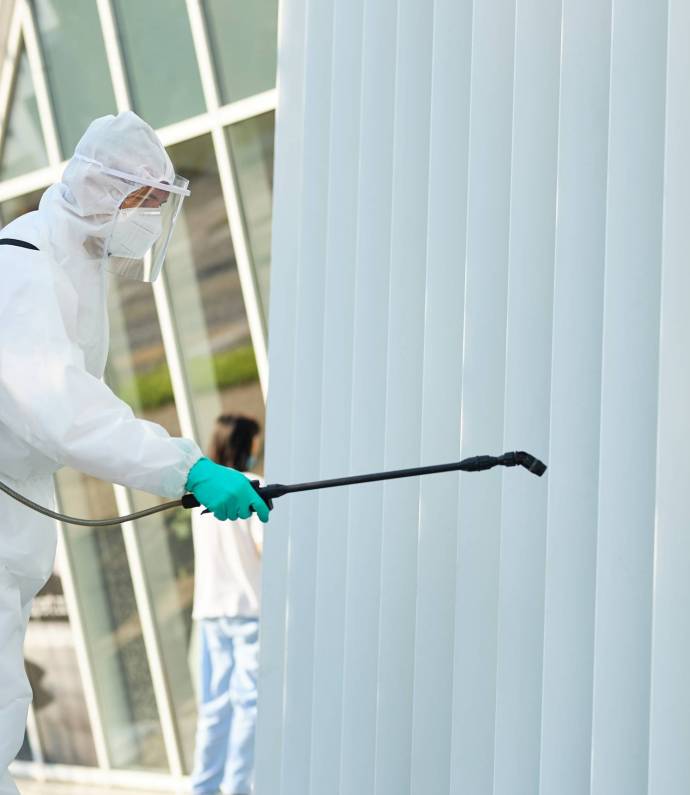 Disinfectant worker in protective suit sanitizing city area in order to prevent spread of COVID-19.